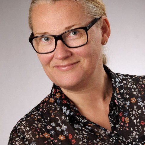 Ingeborg Reichle with blonde hair and glasses smiling 
