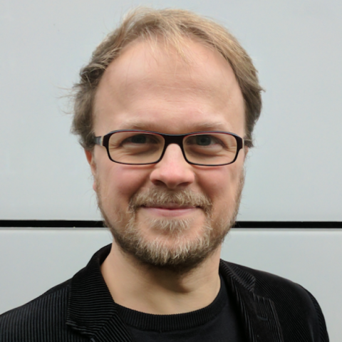 Jöran Muuß-Merholz with glasses, blond hair and beard smiling 