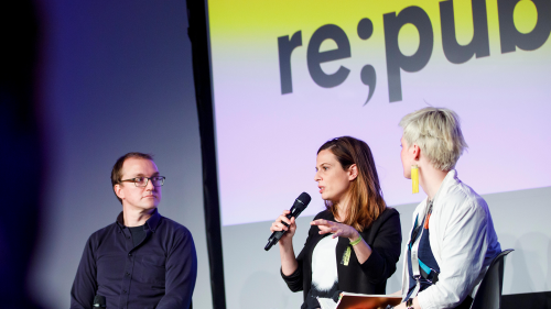 Bühnensituation einer Session bei der re:publica. Drei Sprecher:innen, zwei davon weiblich, eine hält ein Mikro in der Hand.