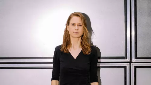 Maren steht vor einer hellen Wand, ihre schulterlangen Haare trägt sie offen.