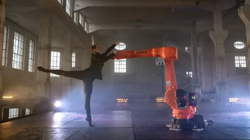 Balletttänzerin tanzt mit einem organen Industrieroboter.