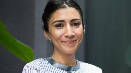 Foto von Urvashi Aneja. Sie lächelt in die Kamera trägt Bluse und Ohrringe.