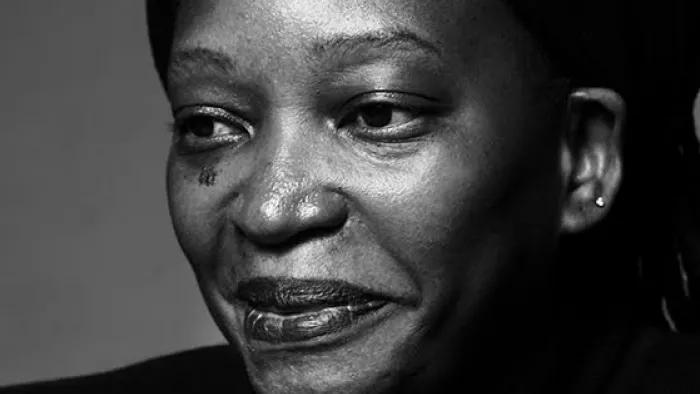 Stella Nyanzi trägt ein Tuch um den Kopf. Sie blickt nach links unten ins Bild.