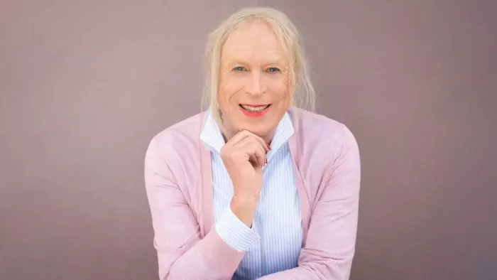 Georgine sitzt vor einem hellen Hintergrund. Sie trägt kinnlange Haare und lächelt in die Kamera.