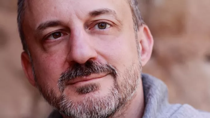 Foto von Gabriel Yoran. Er schaut an der Kamera vorbei, trägt Bart, kurze Hose und ein Hemd.
