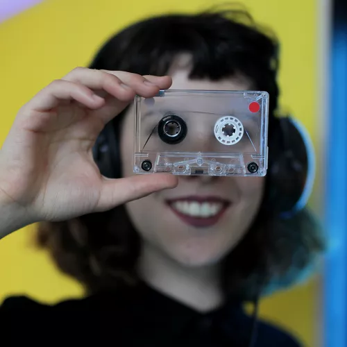 Portrait of Elena holding a cassette in front of her eyes