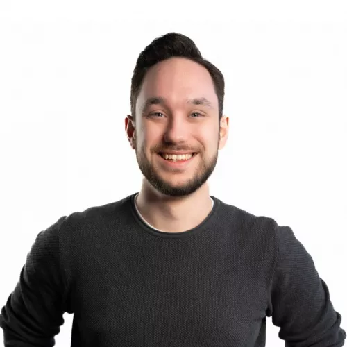 A picture of Melvin Frank, smiling, with short hair and a short beard, wearing a long sleeve black shirt.