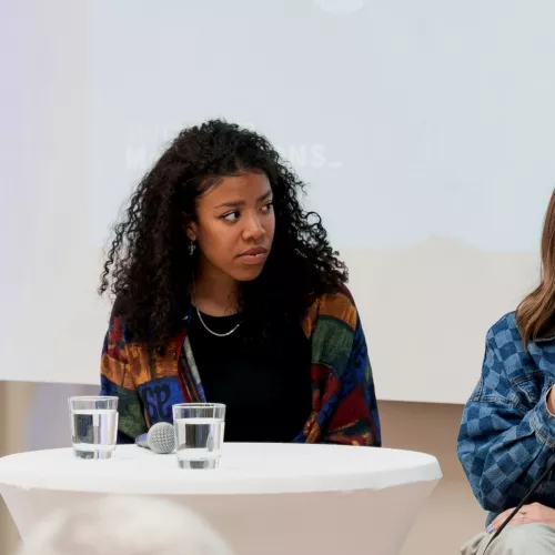 Lia Gavi sitzt zuhörend bei einer Podiumsdiskussion