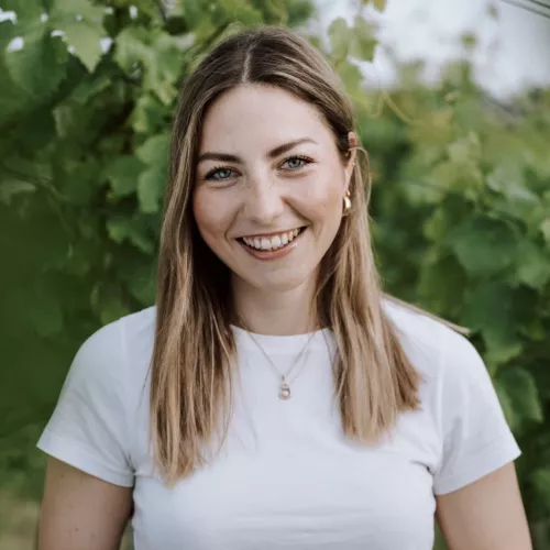junge Frau mit weißem T-Shirt vor grünem Blätterhintergrund