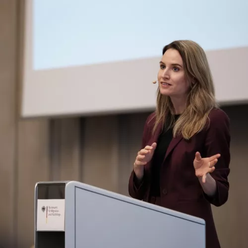 Image depicts Judith Kohlenberger giving a speech
