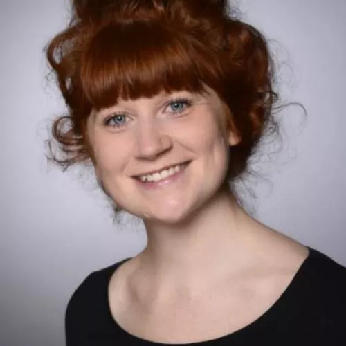 frontales Portraitfoto von Pia Zannoni. Sie hat helle Haut, rote Haare und trägt ein schwarzes, schlichtes Oberteil.