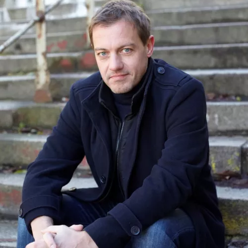 Ein Portrait von Christian Salewski, sitzend auf einer Treppe.