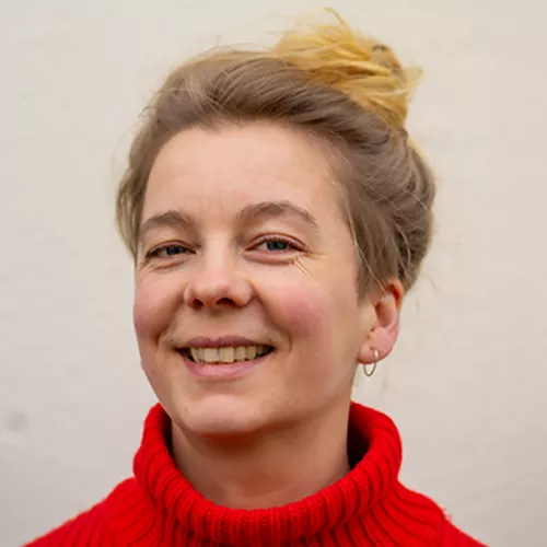 Portrait einer jungen Frau mit Dutt und blonden Haaren sowie rotem Pulli (Svenja Nette)