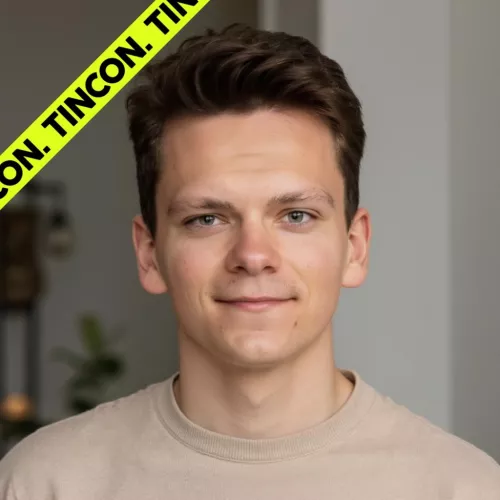 Porträtfoto von einem jungen Mann mit kurzen, gestylten Haaren, trägt ein beiges Sweatshirt