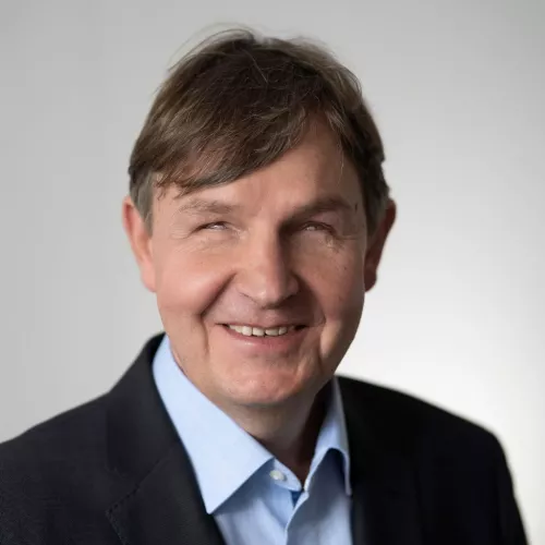 Portrait von Andreas Bethke, er ist mittleren Alters, hat braune Haare und trägt einen Kurzhaarschnitt. Er lächelt in die Kamera. Er trägt ein hellblaues Hemd, dazu ein schwarzes Sakko. DBSV - A. Friese