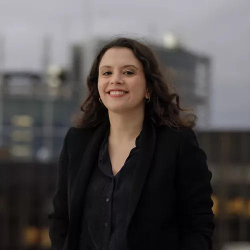 Porttait von Delara, sie lächelt im Hintergrund erkennt man das EU Parlament in Straßburg