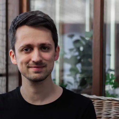Ein Bild von Fabian Navarro mit dunklen Haaren auf einer Korbcouch auf einem Balkon im Hintergrund ist eine Katzensicherungsnetz zu sehen.