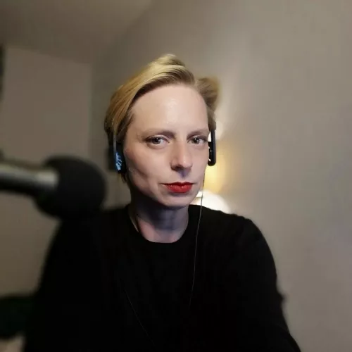 Portraitbild von Laura Hille, weißer Hintergrund und verschwommenes Mikrofon im Vordergrund