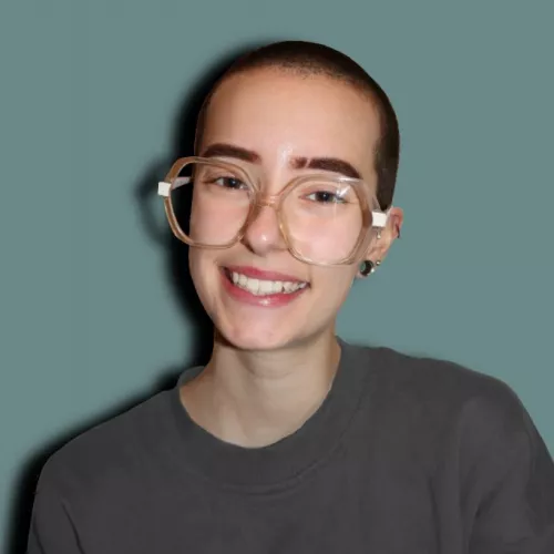Porträtbild einer jungen Person mit Brille vor einem blauen Hintergrund