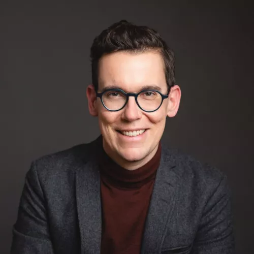 Mann mit dunklen kurzen Haaren und Brille.