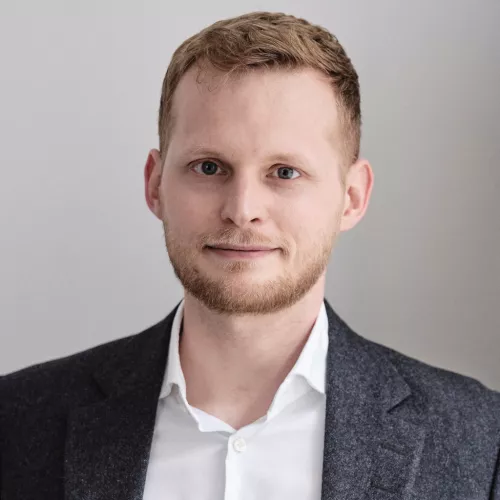 Foto von Jasper Prigge vor einer grauen Wand.