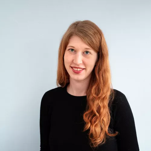 Auf dem Foto steht Lisa vor einem blauen Hintergrund.