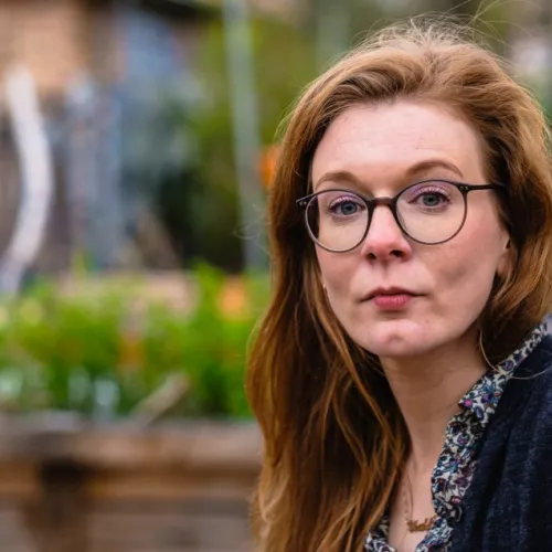 Ein Portrait von Luise Meergans, Außenaufnahme. Im Hintergrund urbaner Raum, Mauern mit Grafitti und Pflanzen.
