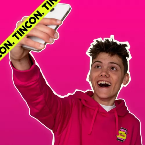 Junger Mann hält ein Smartphone in die Luft und schaut in die Frontkamera