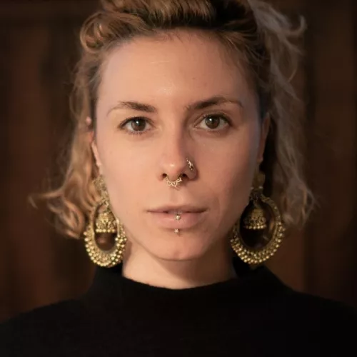 Frau, Zopf nach oben, Ohrringe, Piercings, braune Augen 