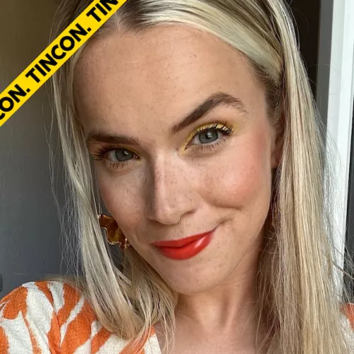 Ein Selfie von Paula Smilla. Sie lächelt in die Kamera und hat offene blonde Haare. Sie trägt eine orangene Bluse mit weißen Streifen.