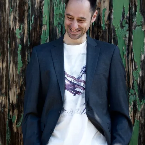 Peter Dreißig - Inhaber des Nachtpeter Verlags - in Jackett und Tshirt, schaut freundlich lächelnd nach unten