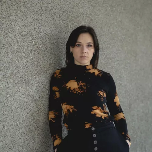 Pia Stendera steht an eine graue Wand gelehnt.