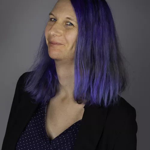 A white woman with shoulder long blue hair smiling