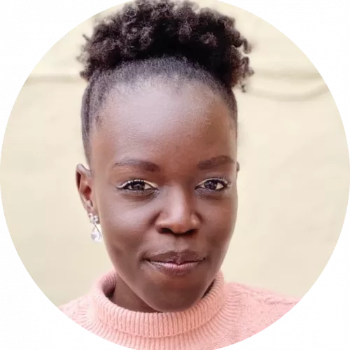 This picture features a woman of African descent with short natural hair, in a pink cardigan