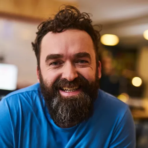 Bild von Christian Lange-Hausstein in blauem T-Shirt, lachend