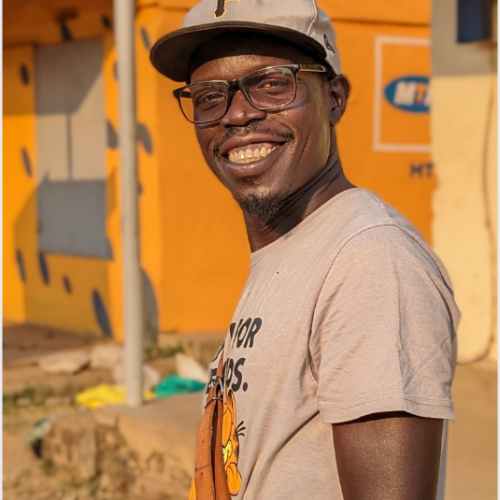 Picture of vuga william a refugee tech advocate smiling and rocking both a grey shirt and hat