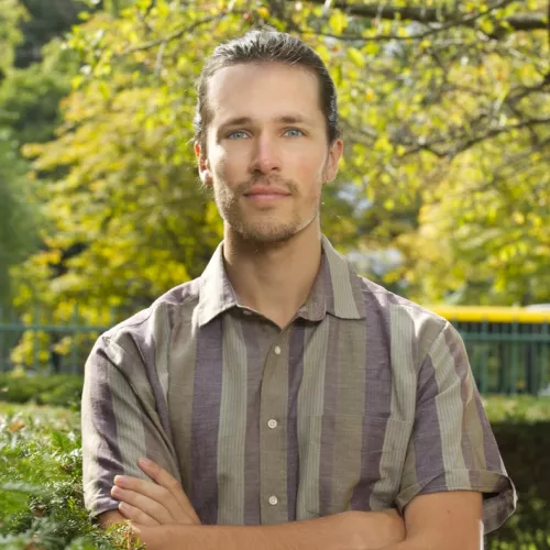 photo of robert gorwa standing with arms crossed with trees in the background