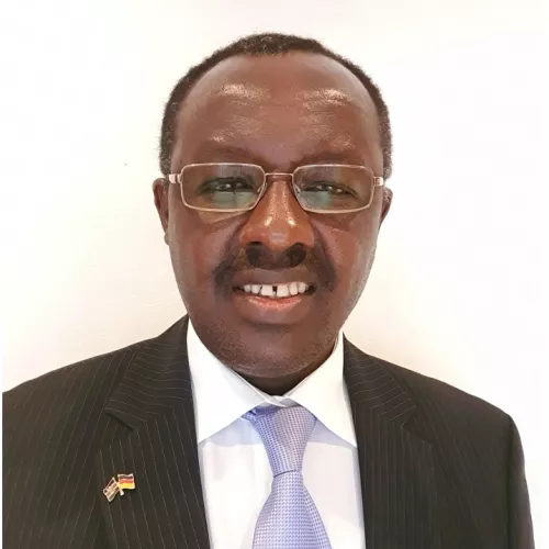 Black man in a black suit with a grey tie, smiling