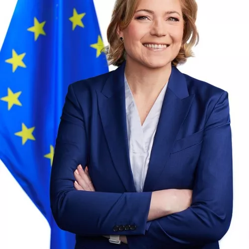 Blonde woman in front of blue EU Flag