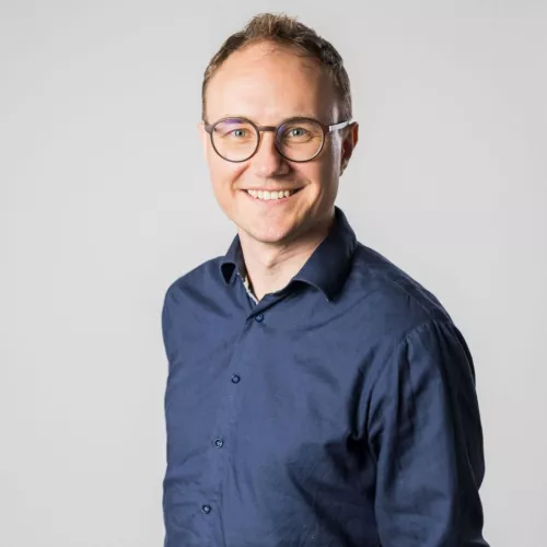 Porträt, weiße, mittelalte Person, kurze Haare, Brille, blaues Hemd