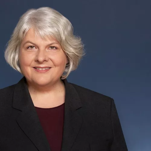 Das Foto zeigt Dagmar Dehmer vor einem blauen Hintergrund.
