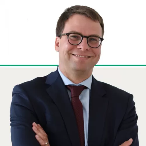 Hier ist Kai Purnhagen zu sehen. Er trägt eine Brille und einen Anzug. Er lächelt freundlich in die Kamera