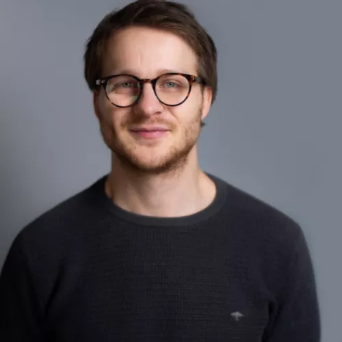 Paul Ramisch vor einem grauen Fotohintergrund.