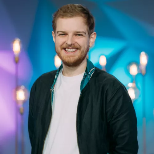 Ein lächelnder Daniel Stolz vor einem lila-blauen Hintergrund