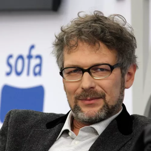 Auf dem Foto, das auf der Bühne der Leipziger Buchmesse in 2017 aufgenommen wurde, blickt Volker Weiß direkt in die Kamera. Er trägt eine Brille, Bart, ein Hemd und ein Jackett.