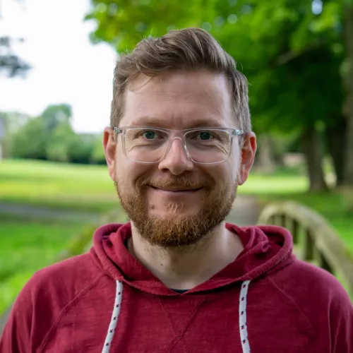 Nahaufnahme von Tim Hantel vor dem Hintergrund einer Grünanlage mit Bäumen