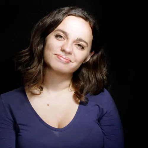 A headshot of a woman with dark hair and a blue t-shirt