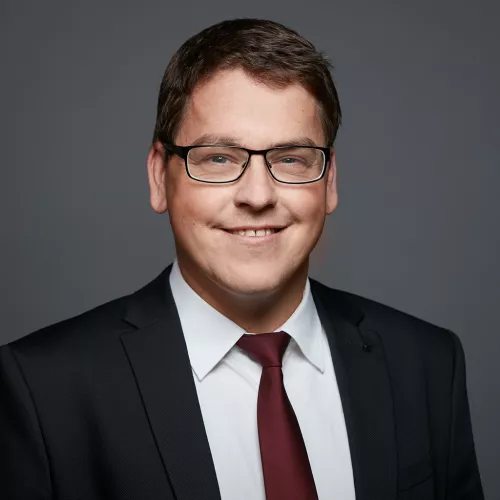 Lars Hohl also know as derPUPE im Anzug mit schelmischen grinsen 