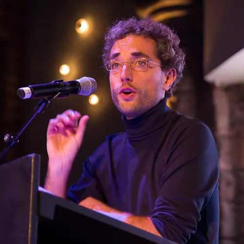 A picture of Michael speaking into a mic at a conference.